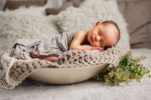 Neugeborenes schläft friedlich in einer Holzschale – Newborn-Fotografie Julia Kippes in Bielefeld