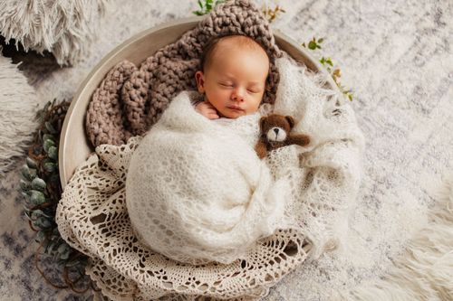 Neugeborenes schläft in einer Schale neben einem Teddybären – Newborn-Shooting Julia Kippes