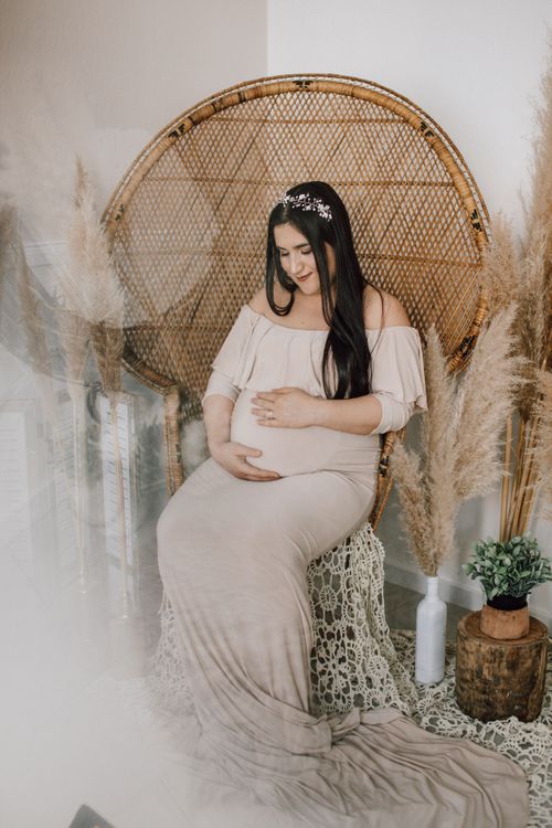 Schwangere Frau in weißem Kleid auf einem Pfauenthron