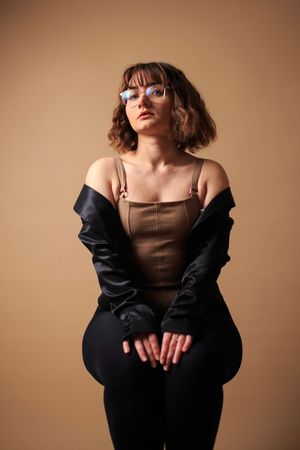 Frau sitzt im Studio auf einem Hocker